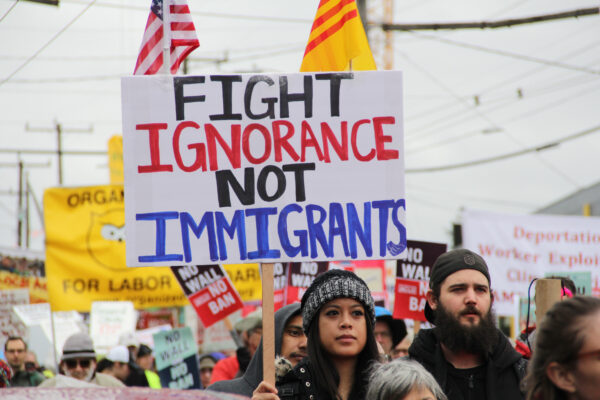 person holding protest sign saying "fight ignorance not immigrants"