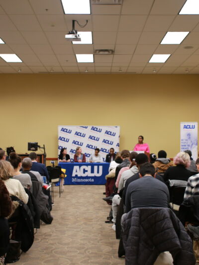 Minneapolis NAACP President Leslie Redmond speaks at a town hall event, where ACLU staff also participated. View is from the back of the room, towards the panelists' table.