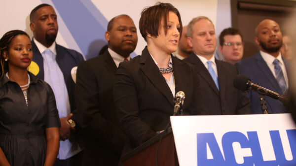 Jen speaks at a podium in the ACLU-MN office, during the Let People Vote press conference