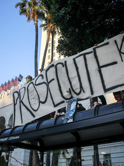 Protesters hold a banner that says, "Prosecute Killer Cops" in front of Los Angeles City Hall during the demonstration.
