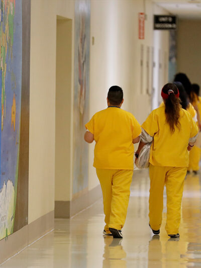Detainees walk past a map of the world in a hallway of a U.S. Immigration and Customs Enforcement (ICE) detention facility.