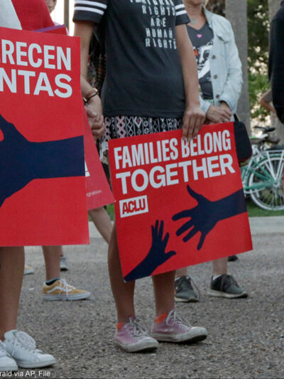 People hold signs that read "families belong together" in both English and Spanish during a vigil.