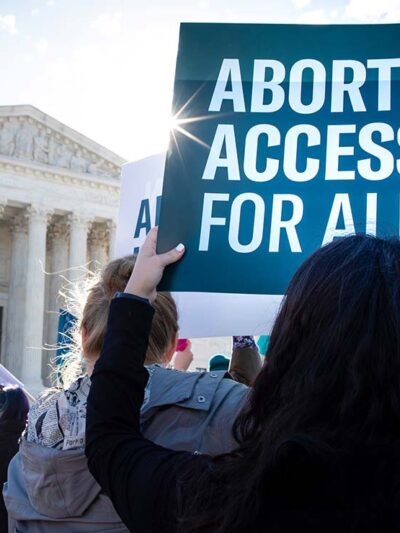 A protestor holds aloft a sign that says "Abortion Access for All" in front of the Supreme Court building in Washington, DC