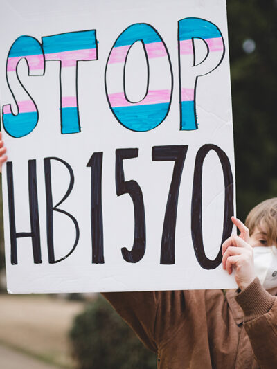 A demonstrator holding a sign with the text "Stop HB1570."