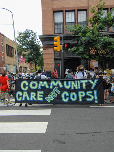 Protesters hold a banner calling for investment in communities, not the police