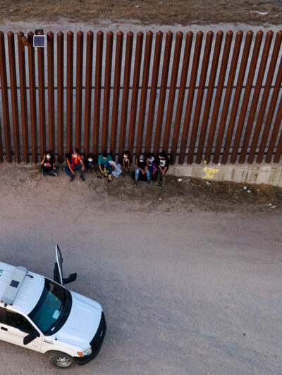 A U.S. Customs and Border Protection vehicle is seen next to migrants after they were detained and taken into custody.