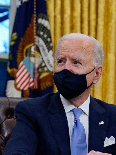A photo of President Biden in the Oval Office wearing a mask.