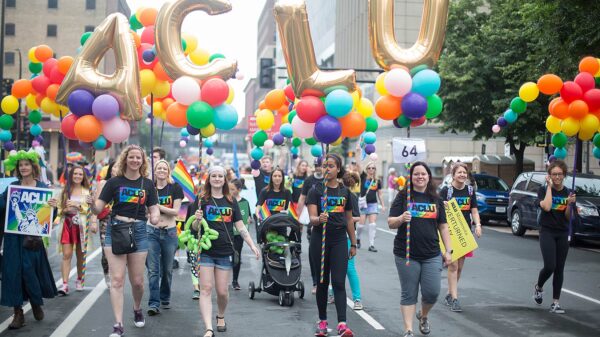 Image of people marching in the Pride parade holding up multicolored balloons reading "ACLU"