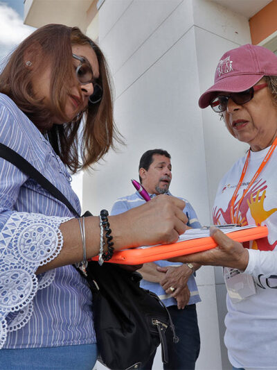 Canvasser Ana M. Vigo, right, registers a woman, left, to vote as a male bystander looks on outside the Polk County Tax Collectors office in Davenport, Fla.
