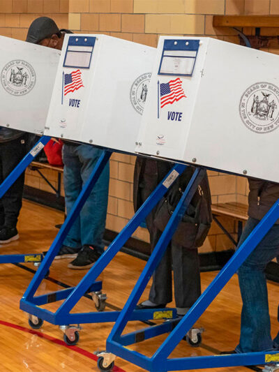 Four people, with their faces and bodies hidden behind voting privacy shields, are casting their votes for the midterm elections on Election Day November 08, 2081 in a New York City public school.