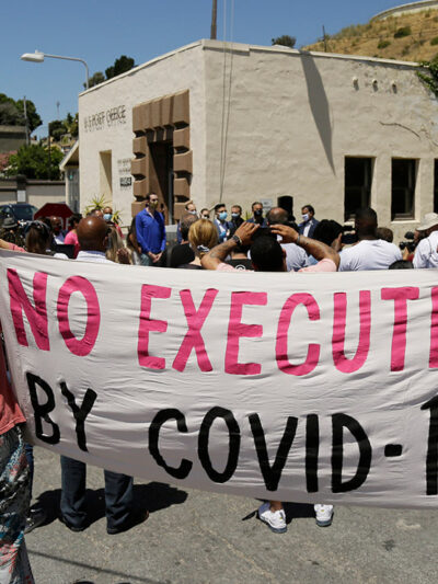 People hold up a banner saying "No Execution by Covid-19."