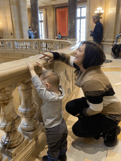 ACLU-MN client Jennifer Schroeder leans against the Capitol rotunda railing with her 2-year-old son.