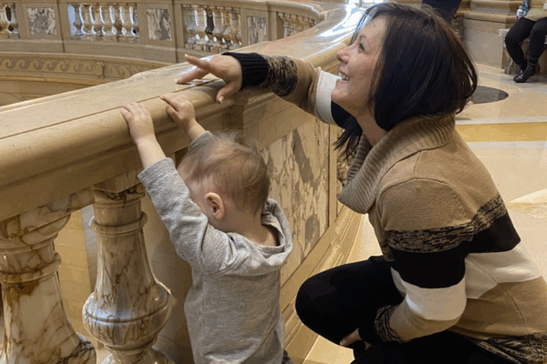 ACLU-MN client Jennifer Schroeder leans against the Capitol rotunda railing with her 2-year-old son.