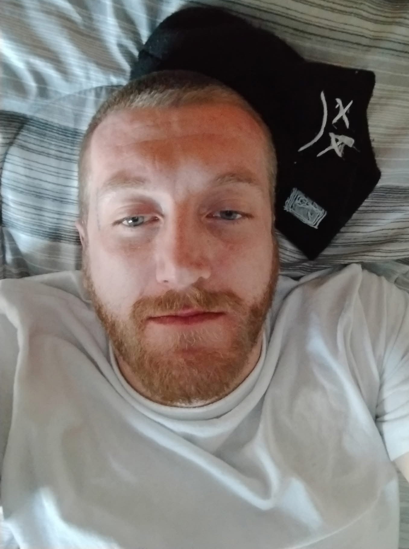 Headship of Josh wearing a white t-shirt and a black and a background of black and white stripes.