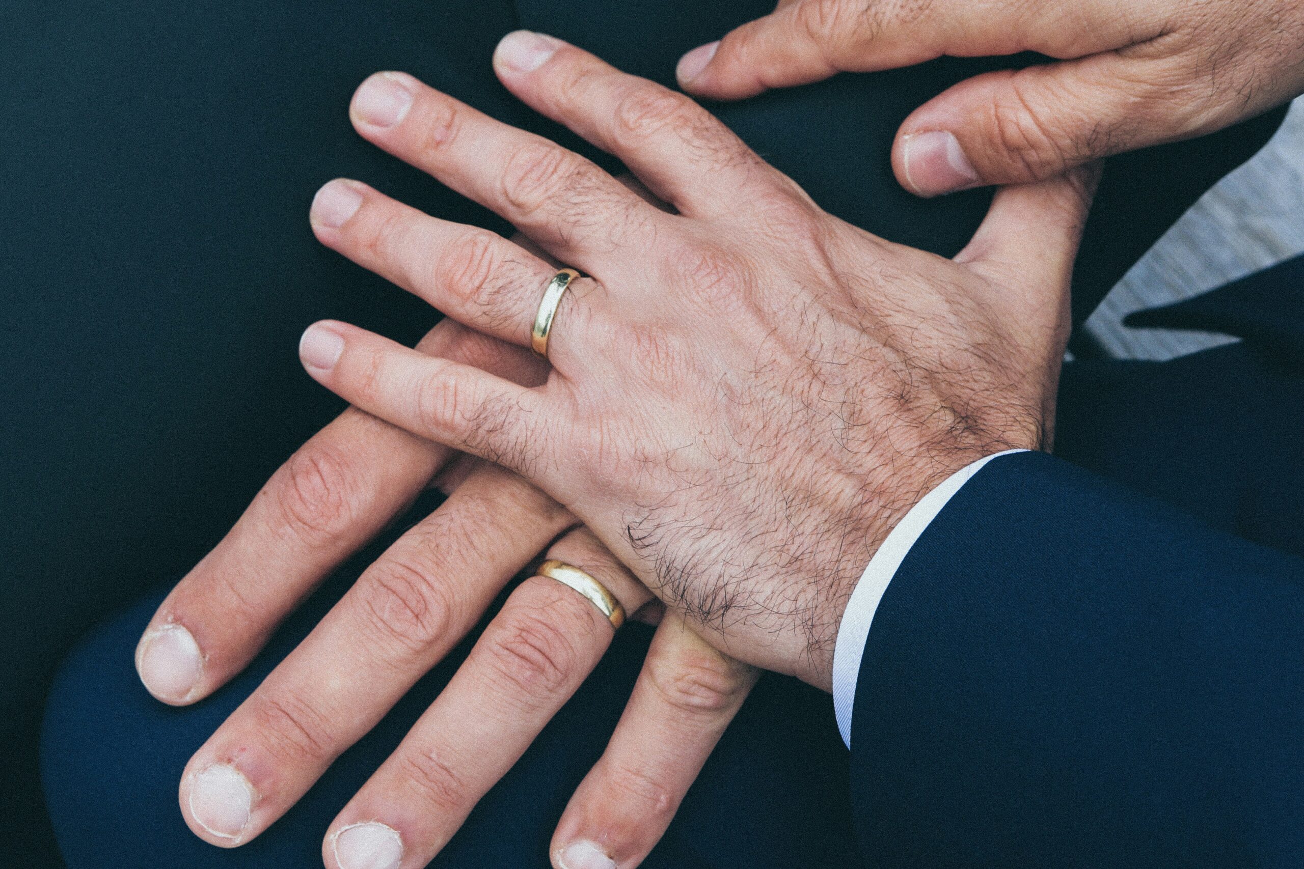 Photo of one hand on top of another, both wearing wedding rings