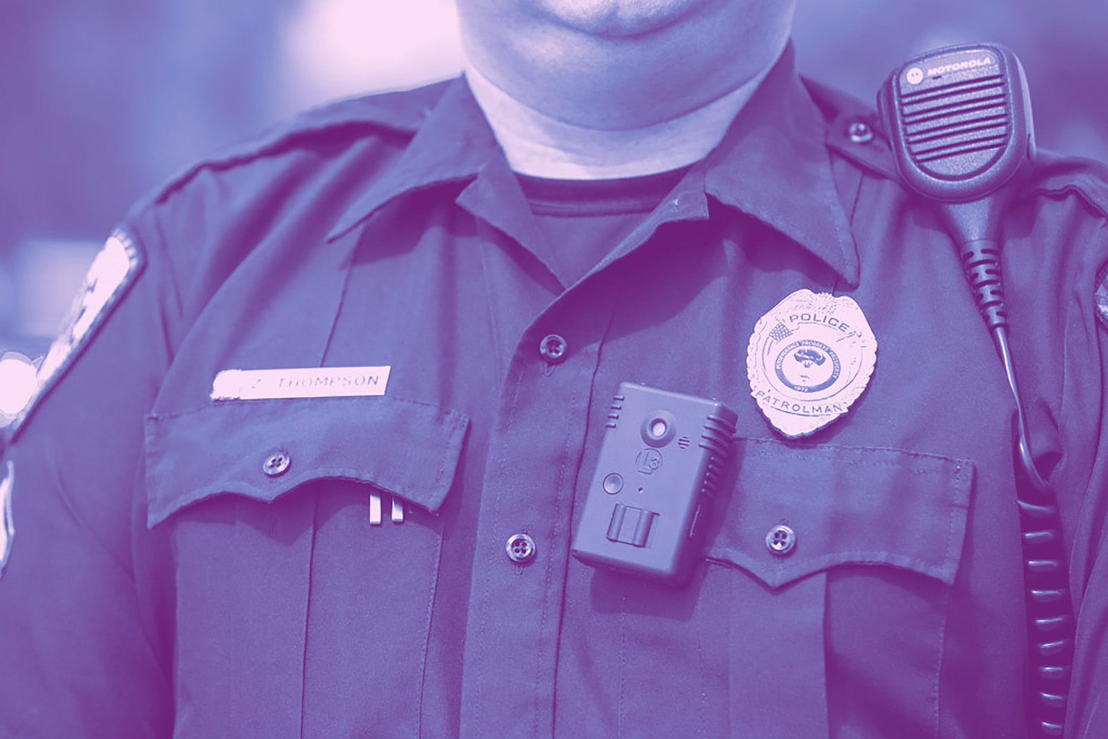 Photo of police wearing his badge, body worn camera and radio.