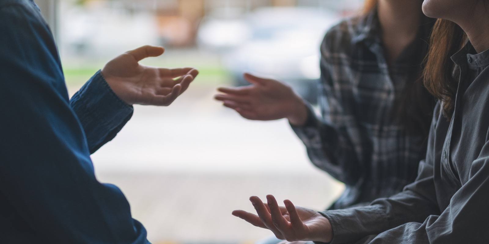 A group of people in a discussion. The focal point is their hands gesturing to one another.