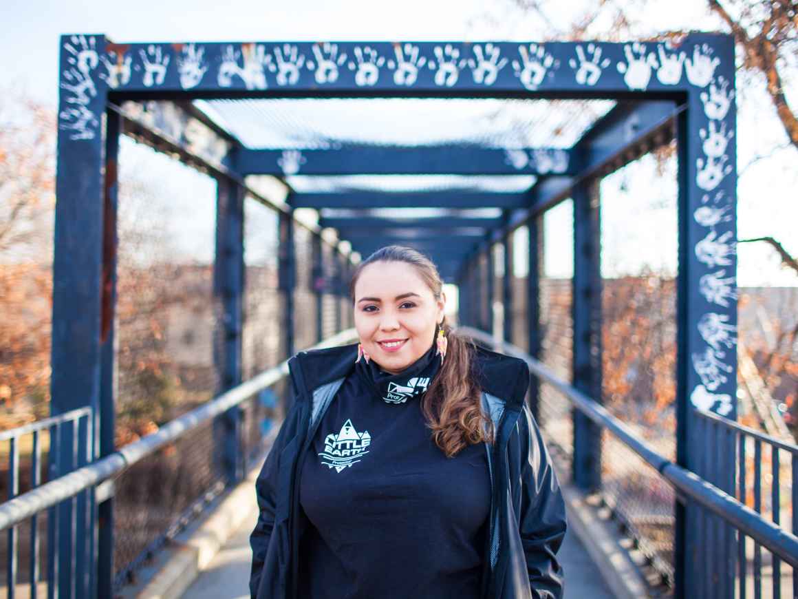 Photo of Rita standing on a blue walking bridge with white handprints.