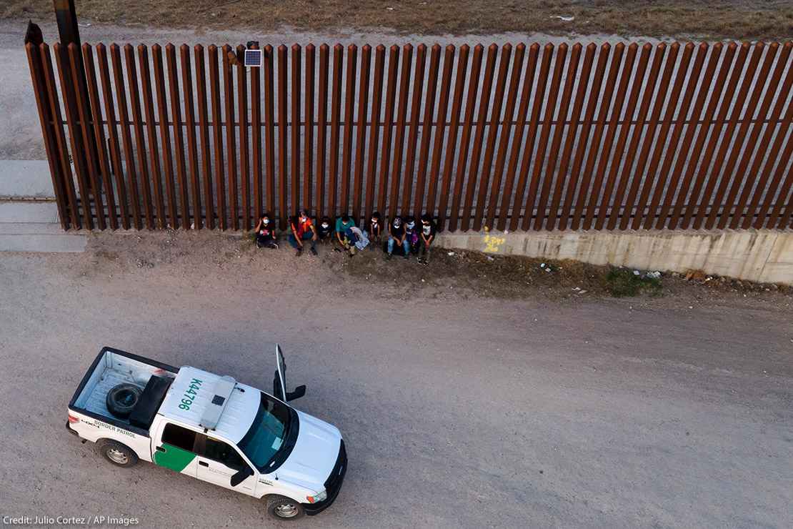 A U.S. Customs and Border Protection vehicle is seen next to migrants after they were detained and taken into custody.