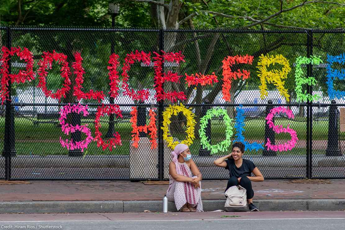 A sign made out of confetti that reads "Police Free Schools" on a gate during a Black Lives Matter protest.