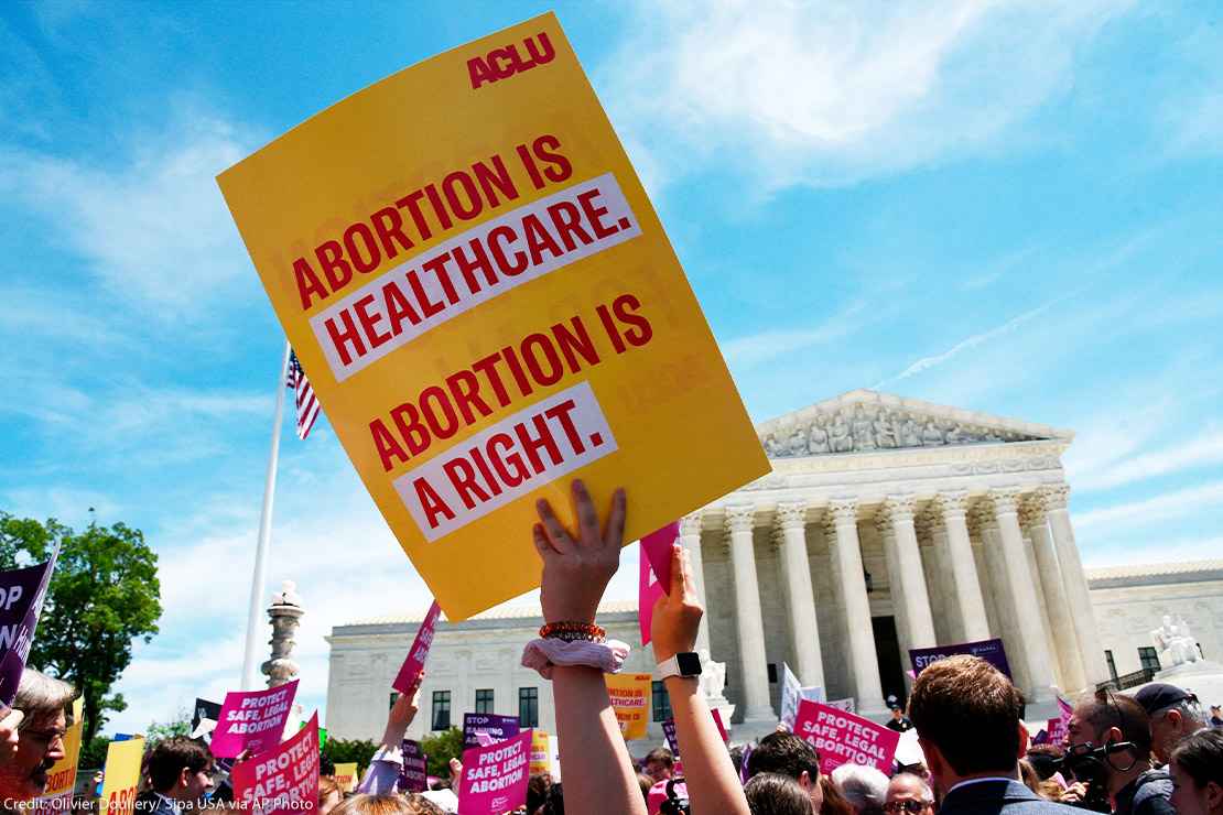 Pro-abortion activist holds ACLU placard that reads "Abortion is healthcare. Abortion is a right." during a rally at the Supreme Court