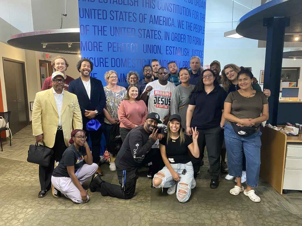 Photo of the 10 Smart Justice Fellows and community partners posing in front of a blue wall. 