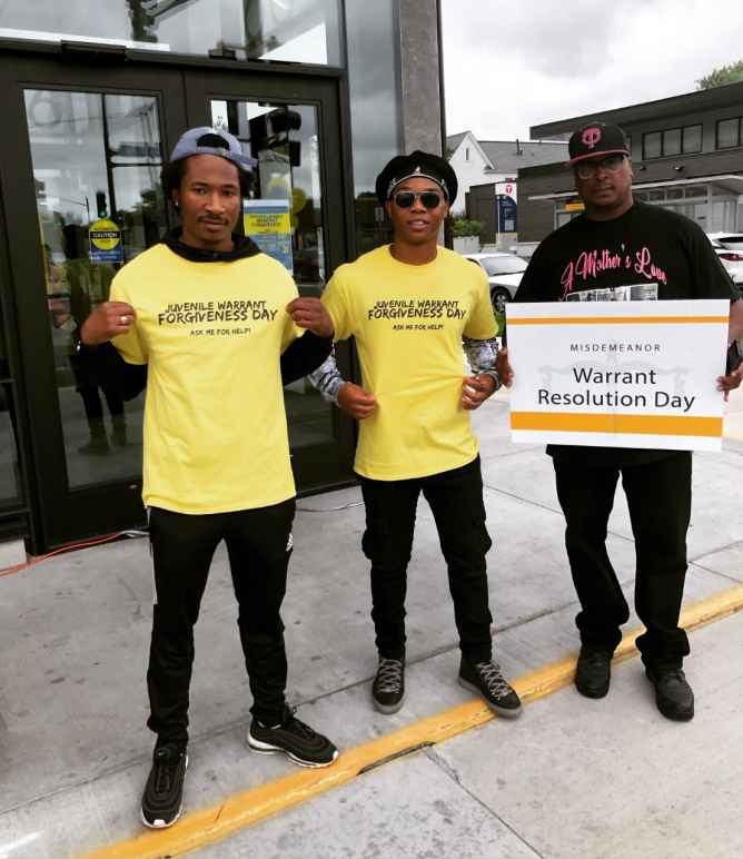 A team of volunteers outside the event displays their yellow event t-shirts which read: "Juvenile Warrant Forgiveness Day: Ask me for help"