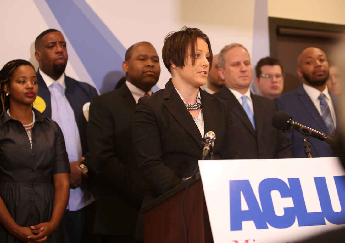 Jen speaks at a podium in the ACLU-MN office, during the Let People Vote press conference
