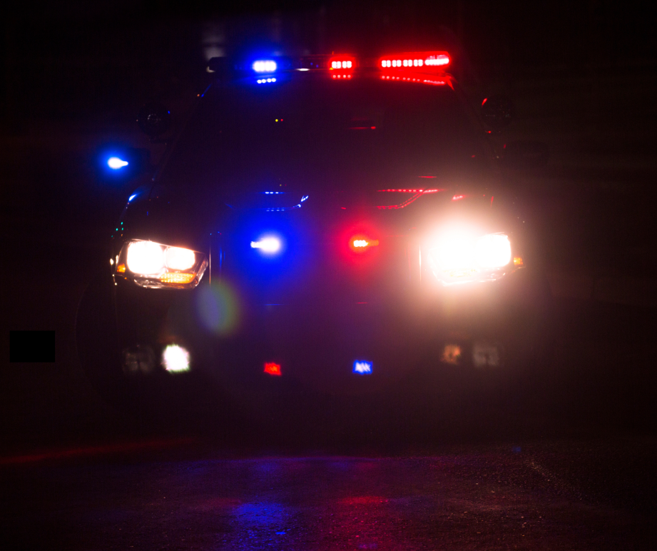 Photo of front of a police car with all lights on at night.