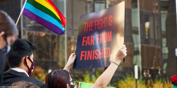 Someone holding a sign that says The Fight Is Far From Finished.