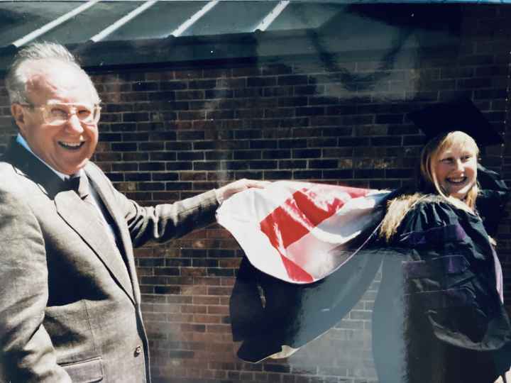 Teresa Nelson on the right in her graduation cap and gown and her father on the left.