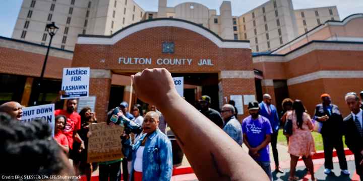 Protester with raised fist in the air at Fulton County Jail after the death of Lashawn Thompson.