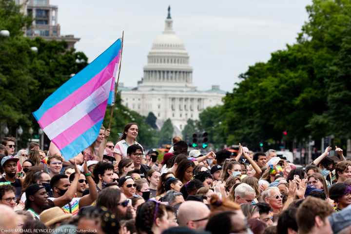 Trans flag flown at Capital Pride parade in Washington, DC, with the US Capitol in the background.