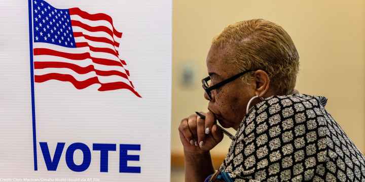 A profile view of a woman in a voting booth.