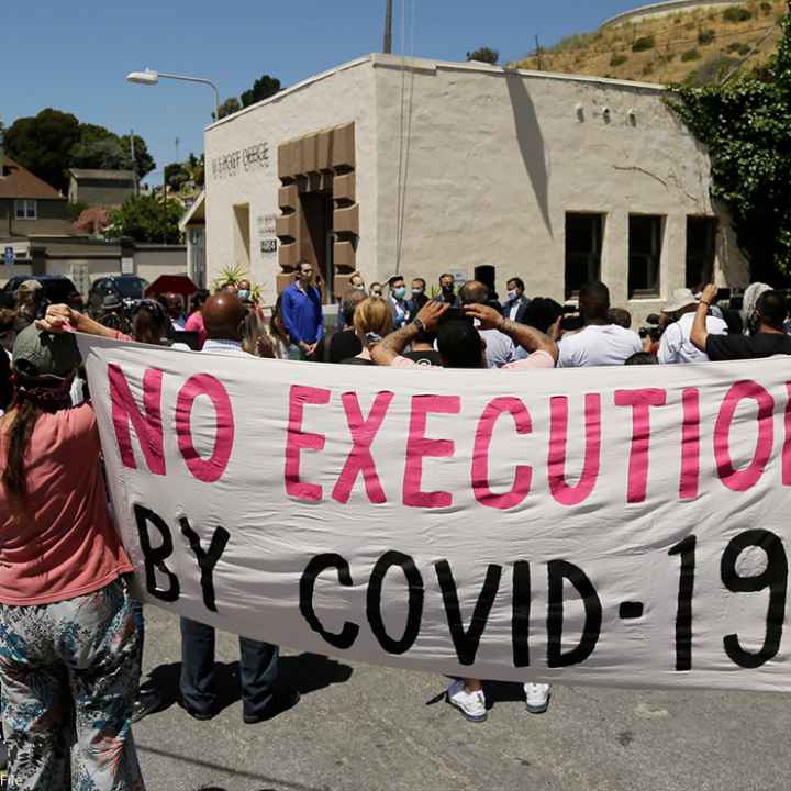 People hold up a banner saying "No Execution by Covid-19."