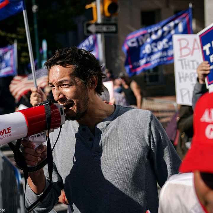 A man uses a bullhorn as he demonstrates with supporters of Donald Trump outside the Pennsylvania Convention Center