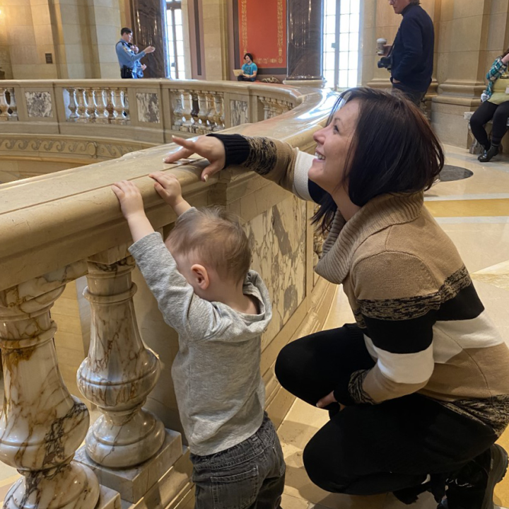 ACLU-MN client Jennifer Schroeder leans against the Capitol rotunda railing with her 2-year-old son.