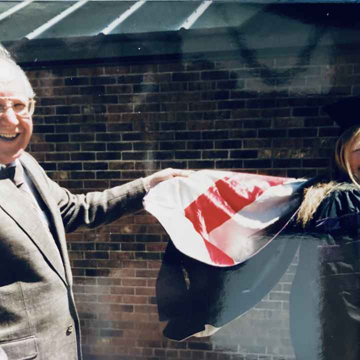 Teresa Nelson on the right in her graduation cap and gown and her father on the left.