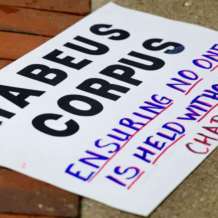 A sign reading " HABEAS CORPUS Ensuring No One is Held Without Charge" lying on the ground.