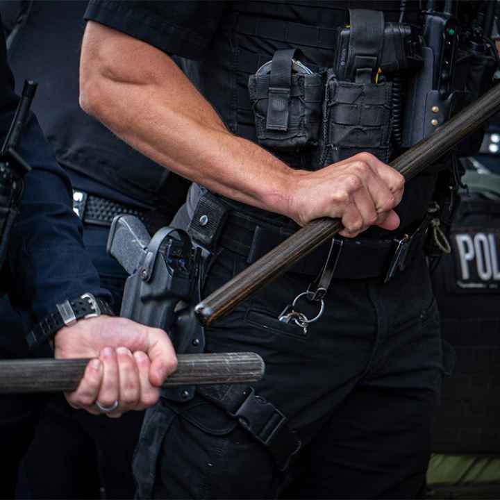 Two cops who are only visible from the chest to waist and are holding batons.